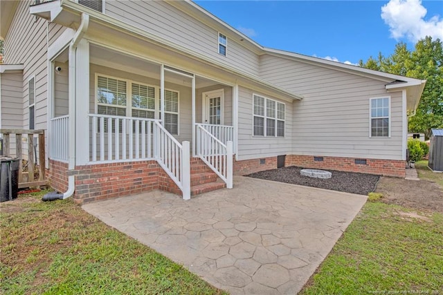 exterior space featuring covered porch, a patio, a front lawn, and crawl space