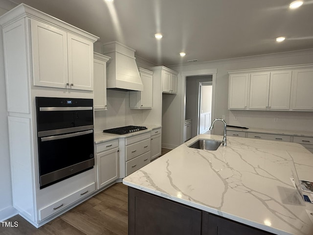 kitchen featuring dark wood-style floors, custom exhaust hood, stainless steel double oven, gas stovetop, and a sink