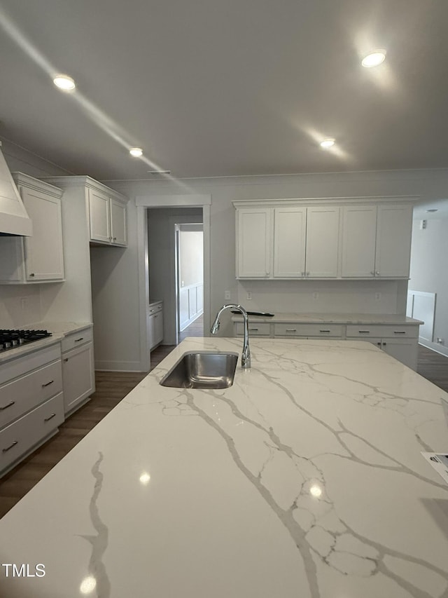 kitchen featuring white cabinetry, gas cooktop, light stone counters, and a sink