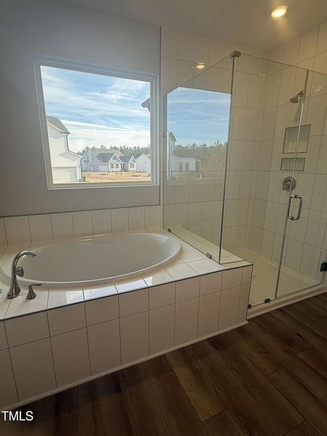 bathroom with a stall shower, a garden tub, and wood finished floors