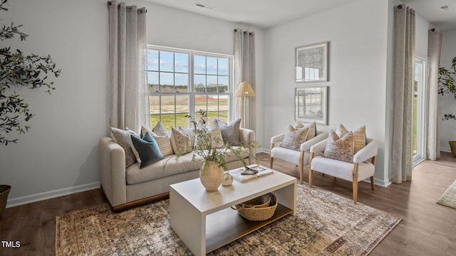 living area featuring visible vents, baseboards, and wood finished floors