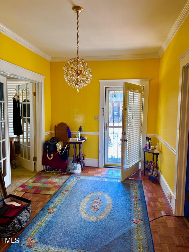 foyer entrance with a notable chandelier, french doors, crown molding, and parquet flooring