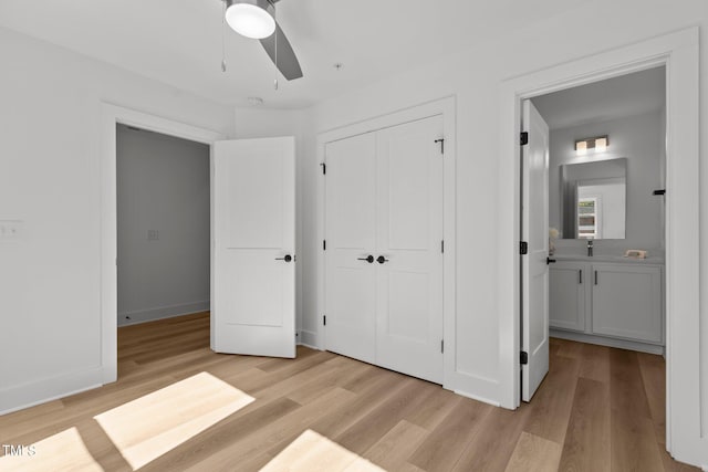 unfurnished bedroom featuring ensuite bathroom, light wood-type flooring, ceiling fan, and a closet