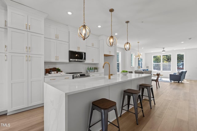 kitchen featuring stainless steel appliances, a kitchen island with sink, and pendant lighting