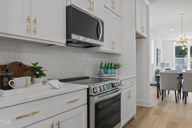 kitchen with stainless steel appliances, white cabinetry, light hardwood / wood-style floors, backsplash, and light stone countertops