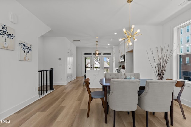 dining room featuring light hardwood / wood-style flooring, french doors, and a chandelier