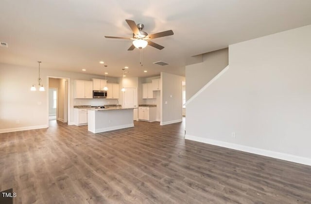 unfurnished living room with baseboards, visible vents, and ceiling fan with notable chandelier