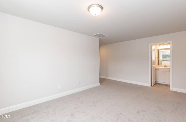 unfurnished room with visible vents, baseboards, a sink, and light colored carpet