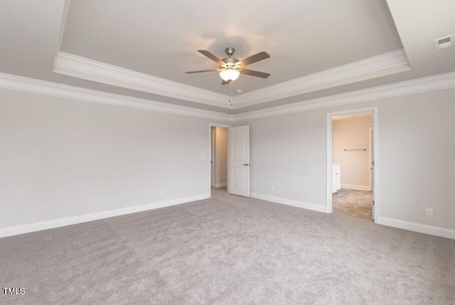 empty room featuring a tray ceiling, crown molding, carpet flooring, ceiling fan, and baseboards