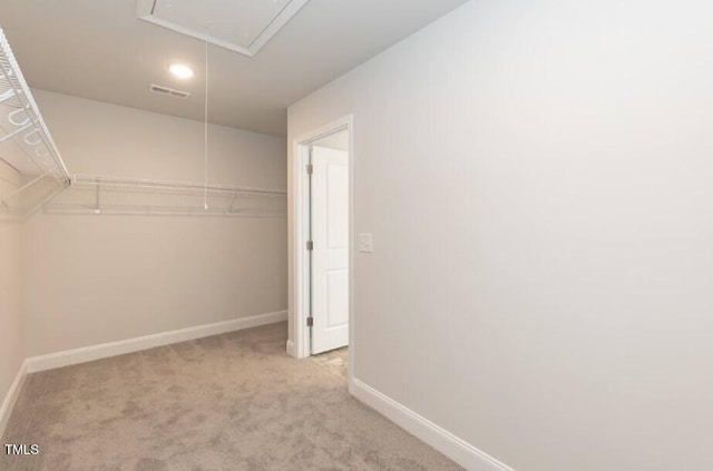 walk in closet with attic access, light colored carpet, and visible vents