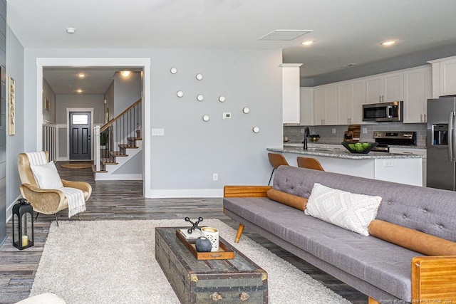living area featuring baseboards, wood finished floors, and stairway