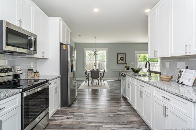 kitchen featuring white cabinets, plenty of natural light, appliances with stainless steel finishes, a sink, and dark wood-style floors