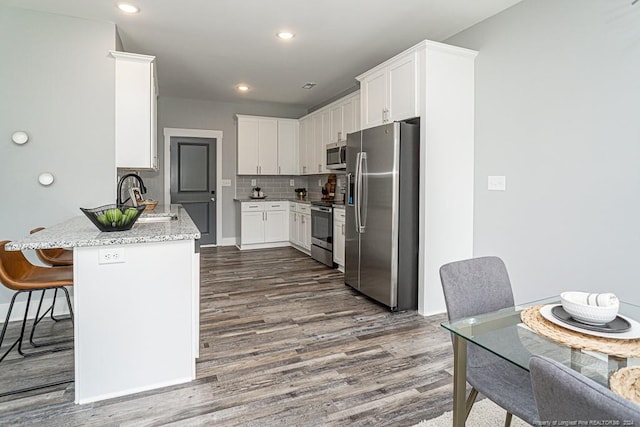 kitchen featuring white cabinetry, a sink, stainless steel appliances, and a peninsula