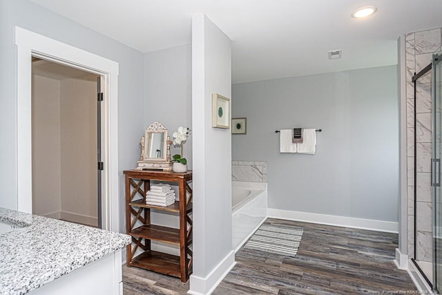 bathroom with wood finished floors, vanity, baseboards, and a shower stall