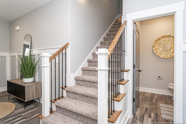 stairs featuring baseboards, wainscoting, and wood finished floors