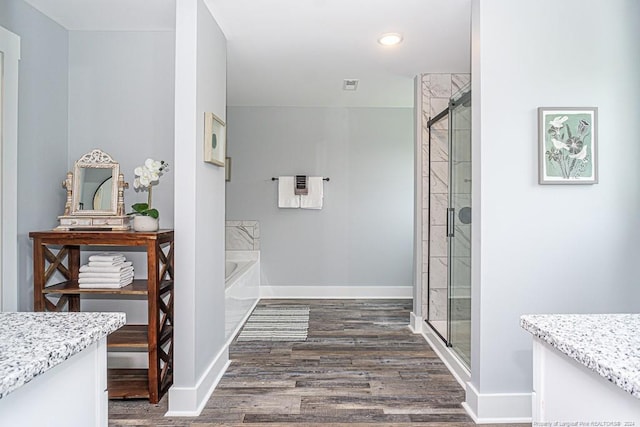 full bath featuring baseboards, wood finished floors, a garden tub, and a shower stall