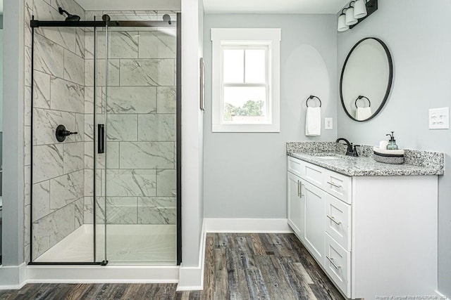 bathroom featuring a stall shower, baseboards, wood finished floors, and vanity
