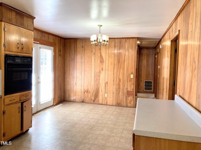 kitchen featuring wood walls, pendant lighting, plenty of natural light, and black oven