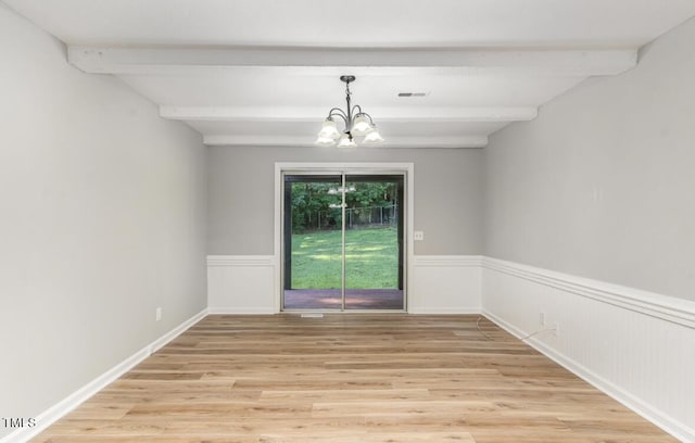 spare room featuring visible vents, wainscoting, light wood-style flooring, beamed ceiling, and an inviting chandelier