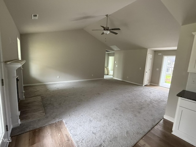 unfurnished living room featuring ceiling fan, vaulted ceiling, and dark colored carpet