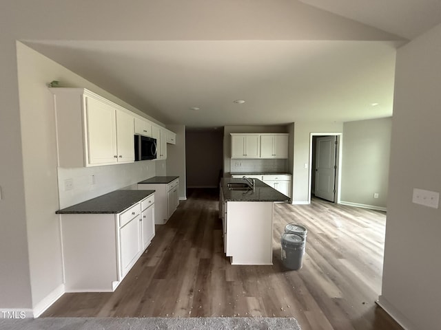 kitchen with decorative backsplash, white cabinets, dark hardwood / wood-style flooring, and dark stone counters