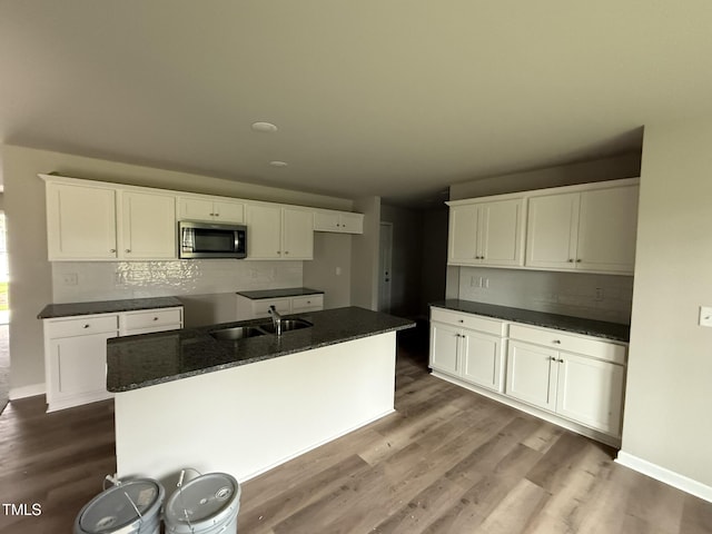 kitchen with tasteful backsplash, sink, a kitchen island with sink, and white cabinets