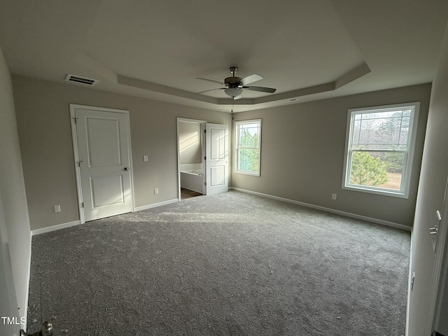 unfurnished bedroom with carpet floors, connected bathroom, ceiling fan, and a tray ceiling