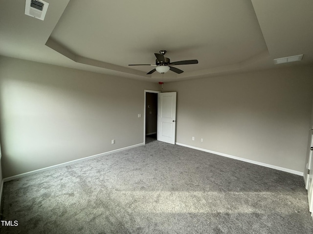 carpeted spare room with ceiling fan and a tray ceiling