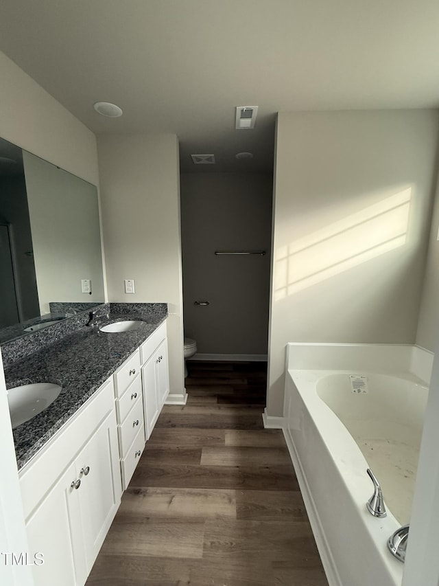 bathroom with wood-type flooring, toilet, vanity, and a tub