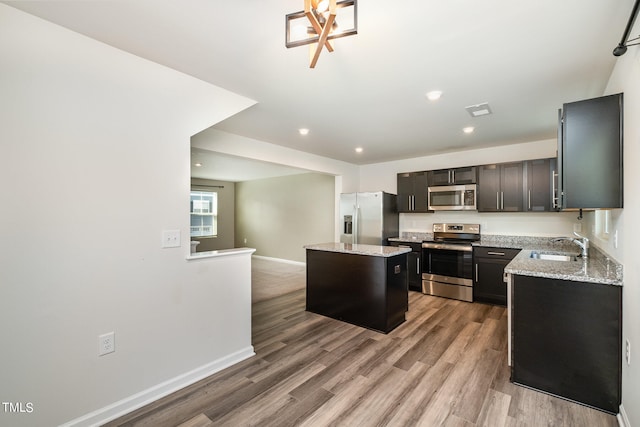 kitchen featuring a center island, light stone counters, appliances with stainless steel finishes, and light hardwood / wood-style floors