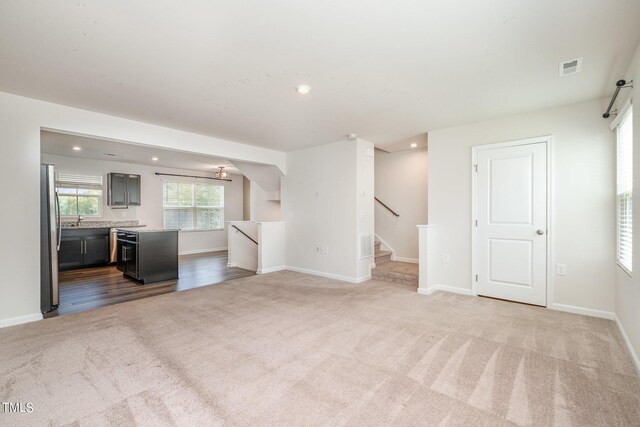 unfurnished living room with sink and carpet flooring