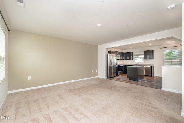 unfurnished living room featuring carpet and sink