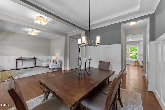 dining space with ornamental molding, hardwood / wood-style floors, and an inviting chandelier