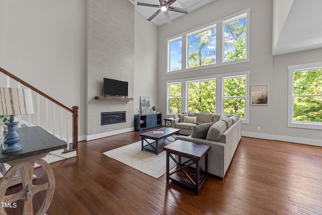 living room with a healthy amount of sunlight, ceiling fan, a high ceiling, and a fireplace