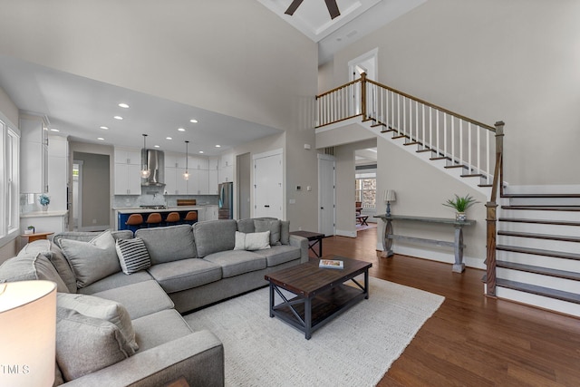 living room featuring light hardwood / wood-style flooring, a high ceiling, and ceiling fan