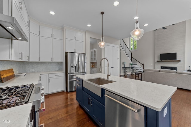 kitchen featuring blue cabinetry, an island with sink, stainless steel appliances, sink, and white cabinetry