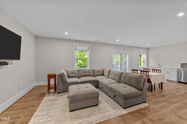 living room featuring light wood finished floors, baseboards, recessed lighting, and a healthy amount of sunlight