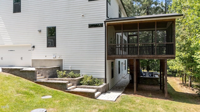 rear view of property with a lawn, a garage, and a sunroom