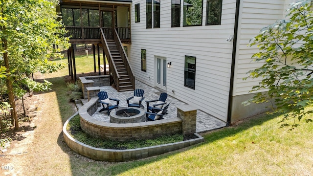 rear view of property with a fire pit and a lawn