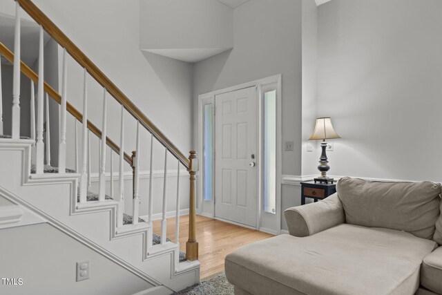 foyer entrance with a towering ceiling and light hardwood / wood-style flooring