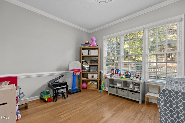 recreation room featuring a textured ceiling, light wood-type flooring, and ornamental molding