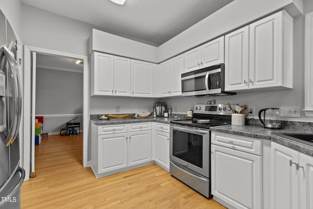 kitchen with light hardwood / wood-style flooring, appliances with stainless steel finishes, and white cabinetry