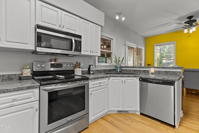 kitchen with appliances with stainless steel finishes, light wood-type flooring, and white cabinetry