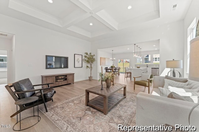 living room featuring a notable chandelier, beam ceiling, light hardwood / wood-style floors, and coffered ceiling