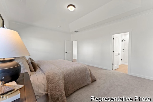 bedroom featuring ensuite bath and light carpet