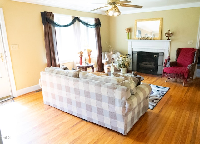 living room with a fireplace, ornamental molding, ceiling fan, and light hardwood / wood-style floors