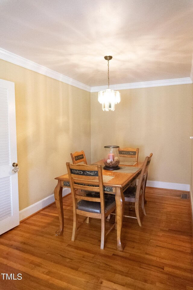 dining area featuring crown molding, a notable chandelier, and hardwood / wood-style floors