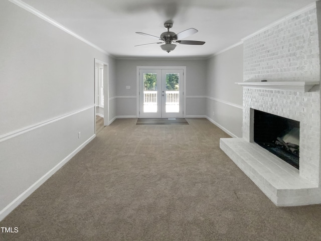 unfurnished living room with ceiling fan, a brick fireplace, french doors, carpet flooring, and crown molding