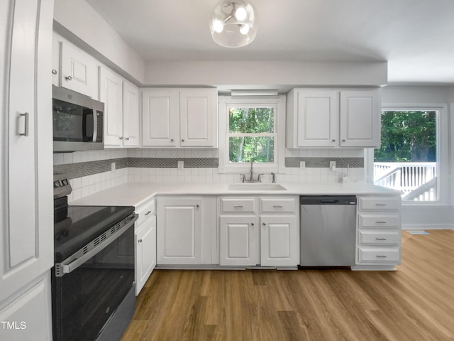 kitchen with light wood-type flooring, sink, stainless steel appliances, and plenty of natural light