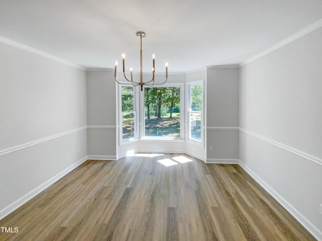 spare room featuring crown molding, hardwood / wood-style floors, and a chandelier